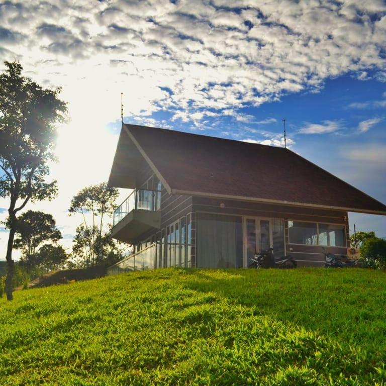 a house sitting on top of a lush green field at Cuckoos Nest in Vagamon