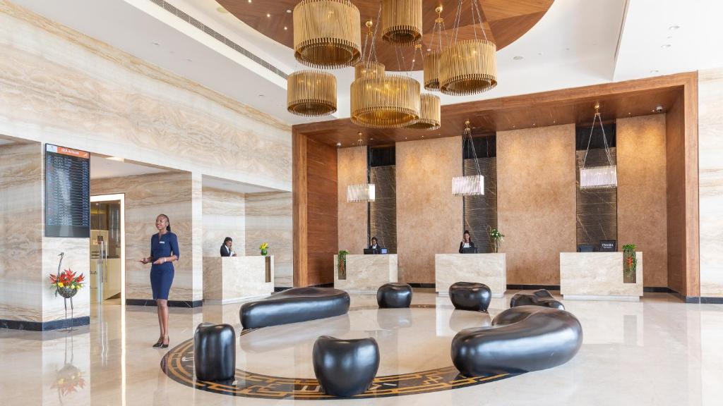 a woman standing in a lobby with a table and chairs at Emara Ole-Sereni-Nairobi Park View in Nairobi