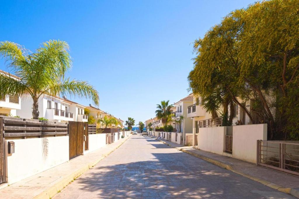 une rue vide avec des palmiers et des bâtiments dans l'établissement Yama's Villa - Polyxenia luxury, protaras, cyprus, à Protaras