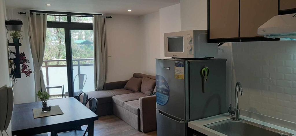 a kitchen and living room with a refrigerator and a couch at Gabs CozyHomes at MegaTower IV Condo, City Center Baguio in Baguio