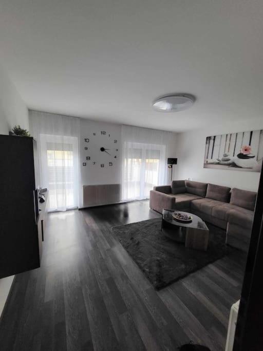 uma sala de estar com um sofá e um relógio na parede em Flower Apartman Győr em Gyor