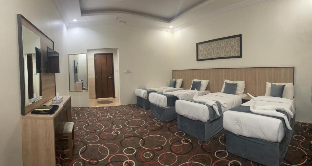 Habitación de hotel con 4 camas y TV en Wedam Six Al Misfalah فندق ودام ستة, en La Meca
