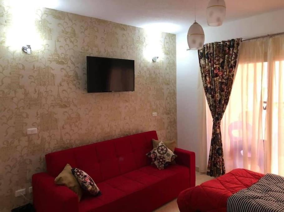 sala de estar con sofá rojo y TV en شقة فندقية مميزة بدمياط الجديدة en Dumyāţ al Jadīdah