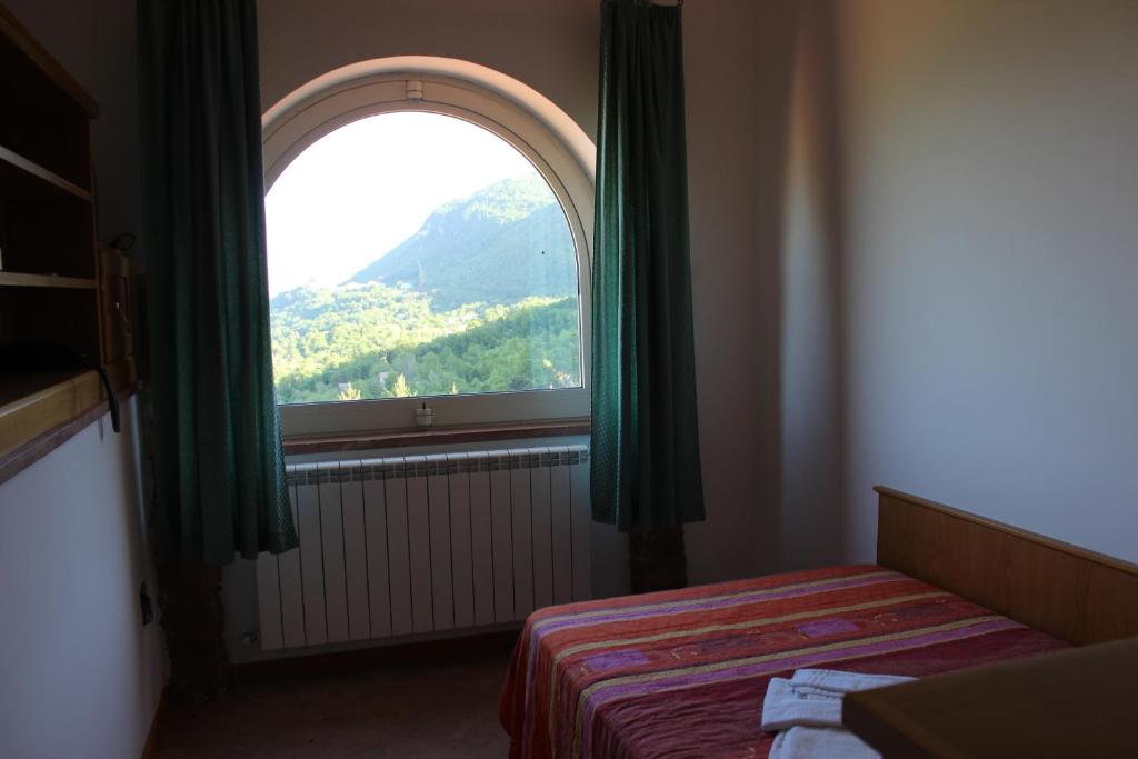 a bedroom with a window with a view of a mountain at Greccio Existence Oasi in Greccio