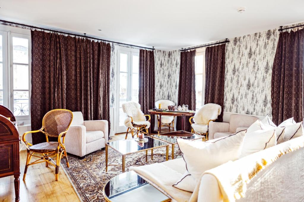 a living room with a couch and chairs and windows at Grand Hotel Soleil d'Or in Megève