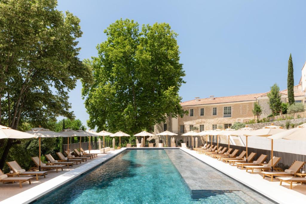 uma piscina com espreguiçadeiras e guarda-sóis em Le Couvent des Minimes Hôtel & Spa L'Occitane em Mane