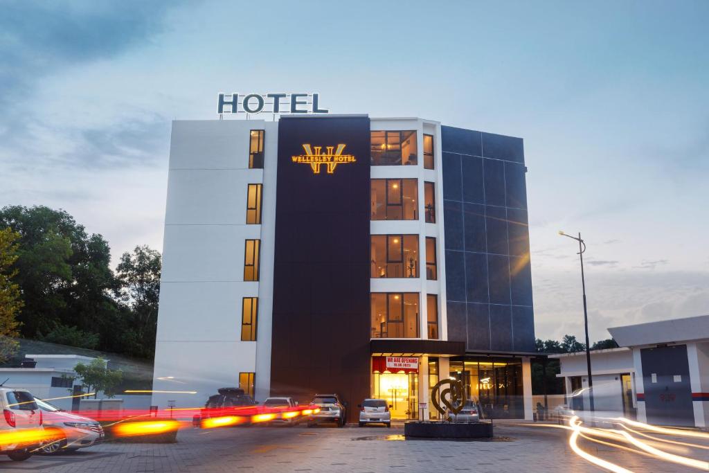 a hotel with cars parked in front of it at Wellesley Hotel in Simpang Ampat