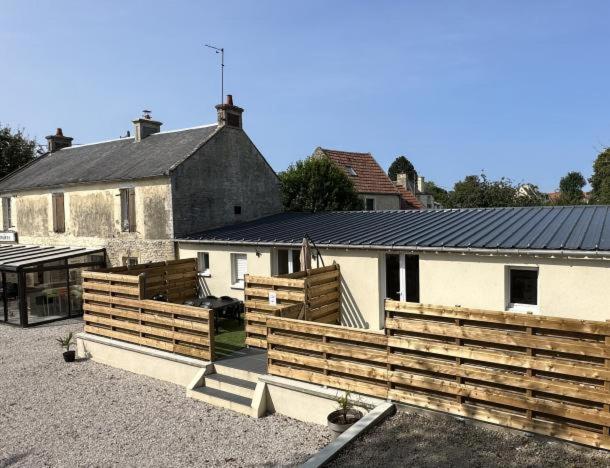 eine Scheune mit Holzzäunen vor einem Haus in der Unterkunft La chaumière in Longues-sur-Mer