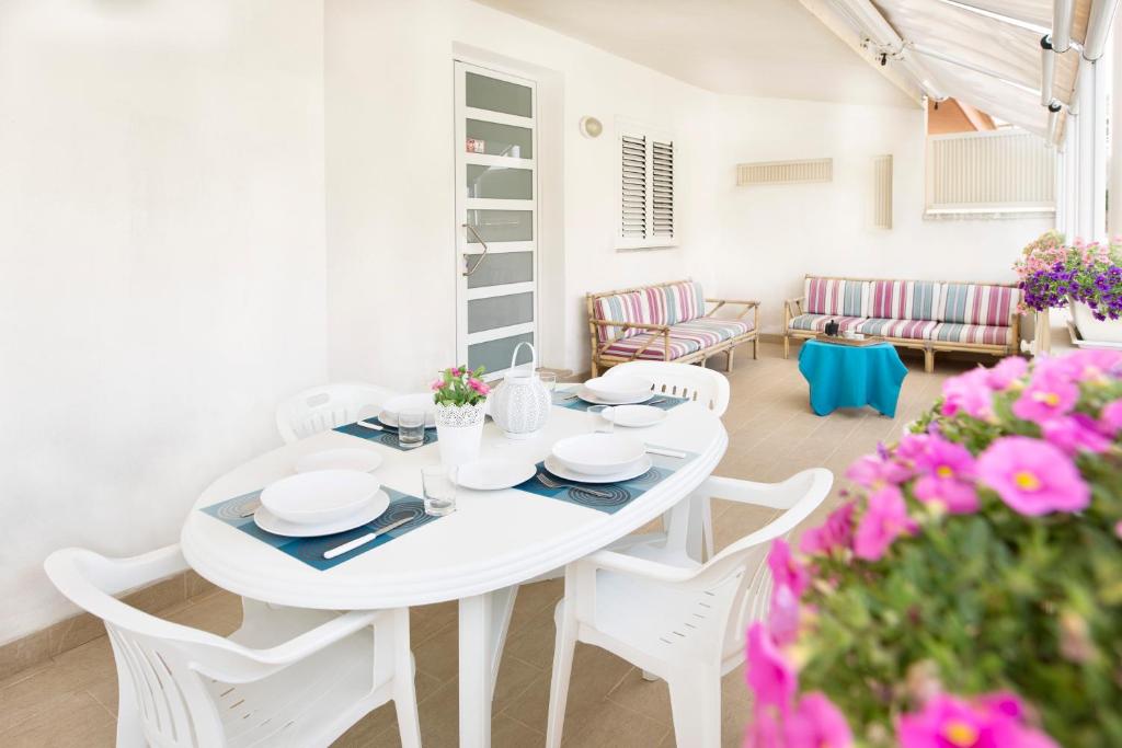 einen weißen Tisch und Stühle in einem Zimmer mit rosa Blumen in der Unterkunft siciliacasevancaze - Villa Torre in Punta Secca