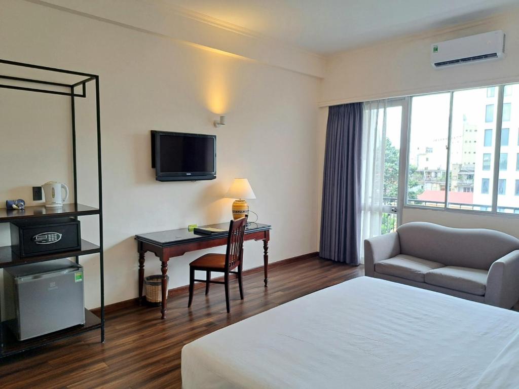 a hotel room with a bed and a desk with a television at Liberty 2 Hotel in Ho Chi Minh City