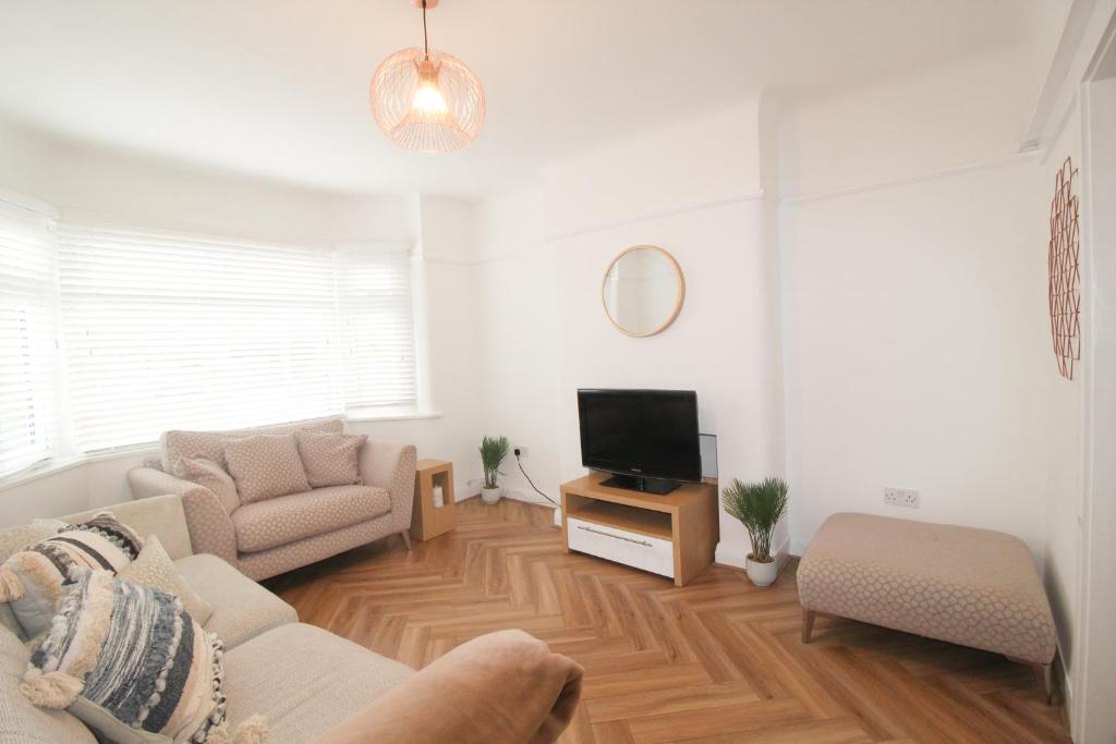 a living room with a couch and a tv at Upton Hidden Garden Retreat in Birkenhead