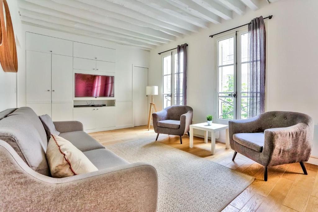 Superbe Appartement Bon marché Saint Germain في باريس: غرفة معيشة مع أريكة وكرسيين