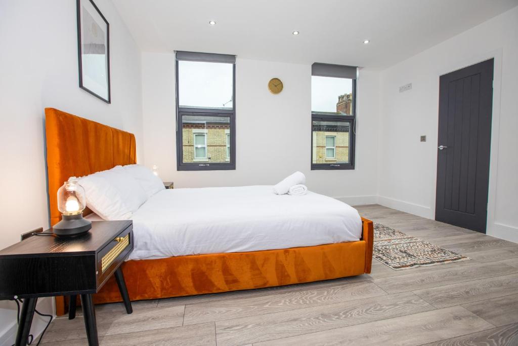 a bedroom with a bed and a desk and two windows at Stylish Stay Near The Stadium Walk To The Action in Liverpool