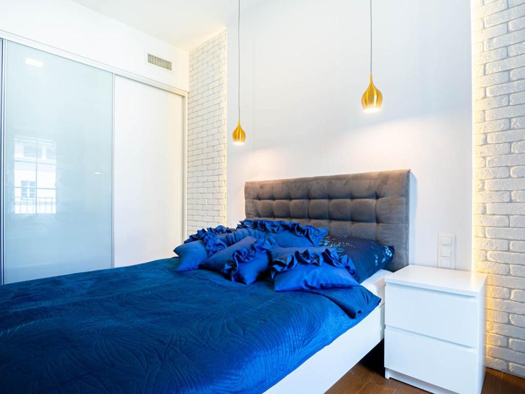 a bedroom with a blue bed and a brick wall at Apartament Sukiennicza in Krakow