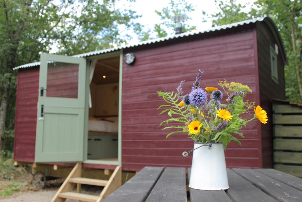 a vase of flowers on a table in front of a house at Cosy Shepherd's Hut with Hot Tub in Church Stretton