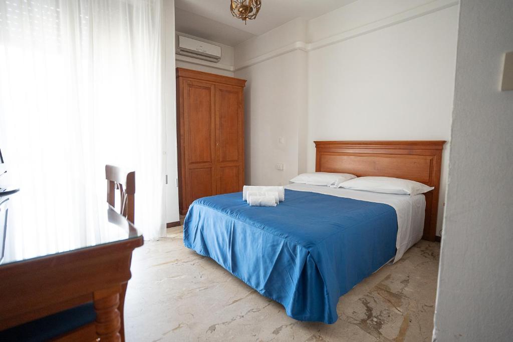 a bedroom with a bed with a blue blanket at Hotel Napoleon in Pontremoli