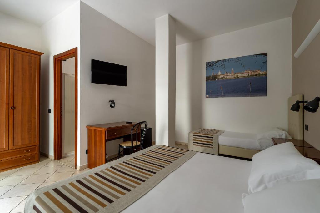 a bedroom with a bed and a desk and a television at Hotel Mantegna Stazione in Mantova