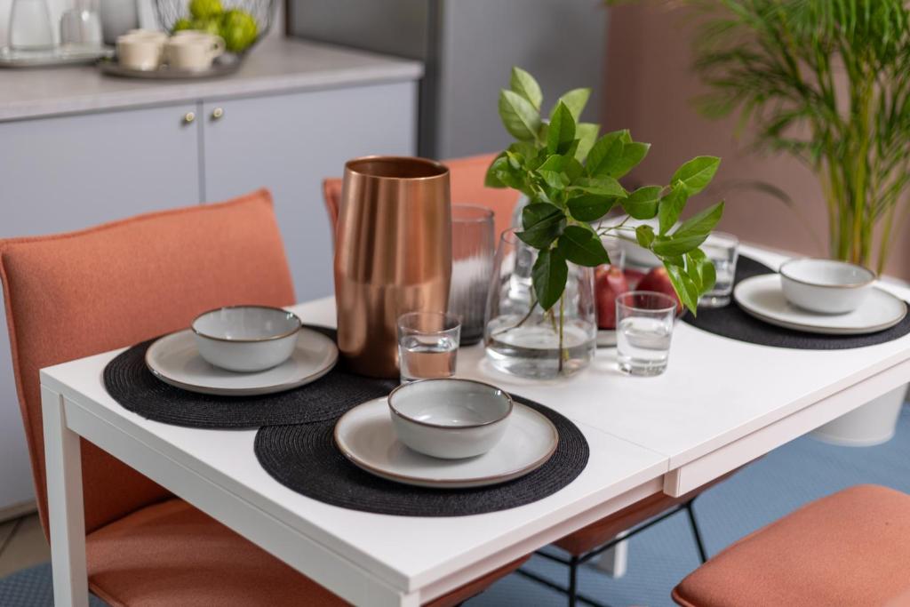 a white dining table with plates and bowls on it at Hostel Krasnal Market Square Wroclaw in Wrocław