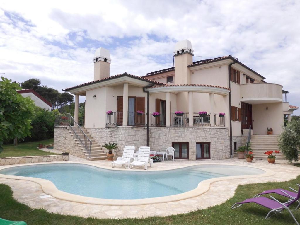 una casa con piscina frente a ella en Guesthouse Villa Lena en Premantura