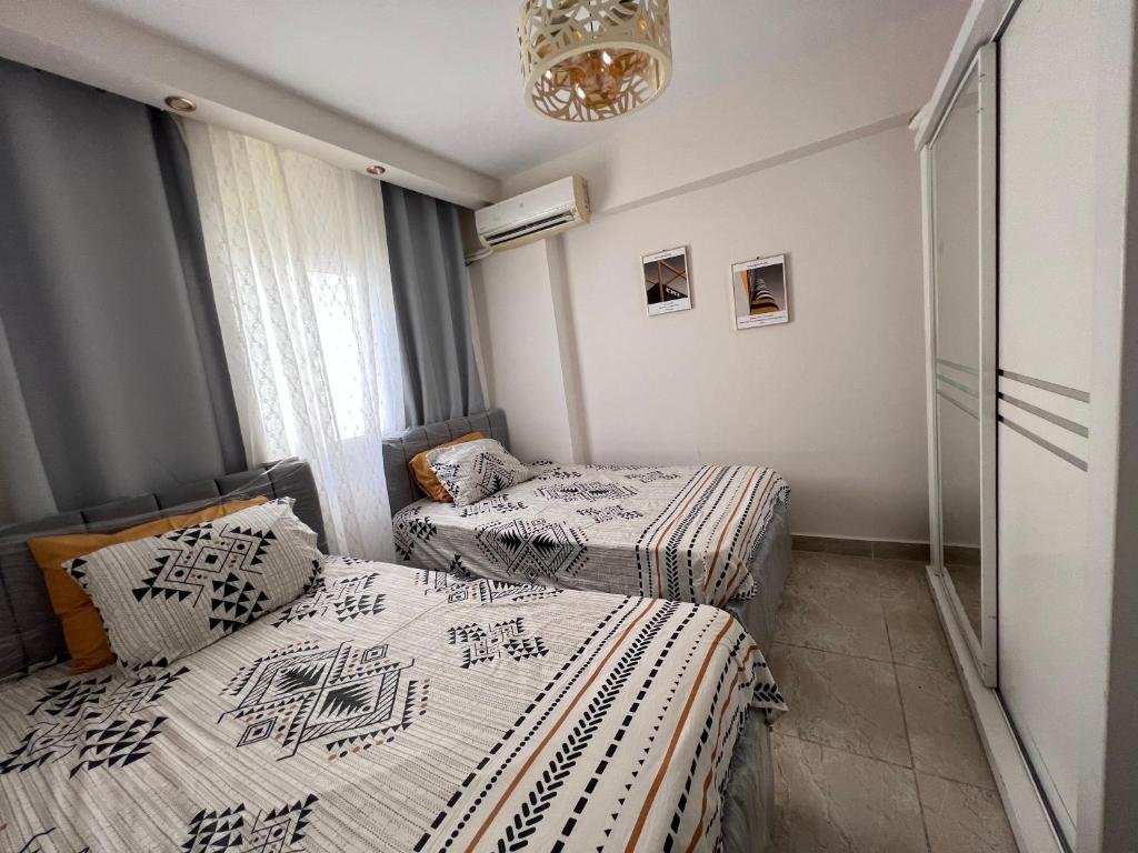 2 camas individuais num quarto com um lustre em فيلا مميزه جدا في الساحل الشمالي ستيلا هايتس Stella Heights - Sidi Abd El-Rahman villa type M em El Alamein