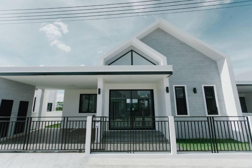 une maison blanche avec une clôture noire dans l'établissement AKIRA Villa, à Buriram