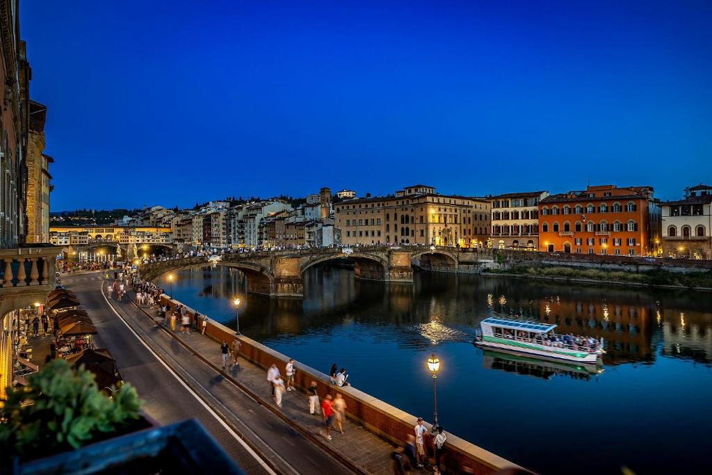 eine Brücke über einen Fluss mit einem Boot darauf in der Unterkunft Rivalta Hotel - Alfieri Collezione in Florenz