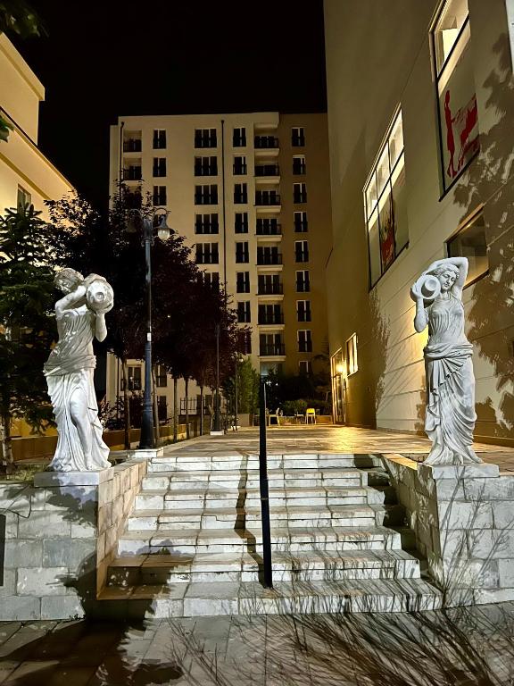 dos estatuas de gatos parados en las escaleras de un edificio en Erika's Place en Pristina