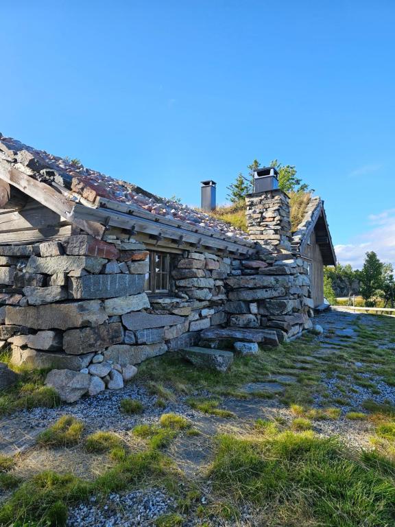 ein altes Steinhaus an der Seite eines Feldes in der Unterkunft Hytte i Hallingdal/Flå in Flå