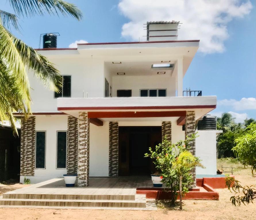 une maison blanche avec un palmier dans l'établissement Villa Moon breeze Nilaveli, à Trincomalee
