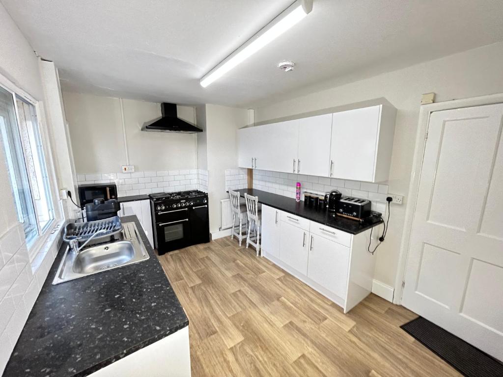 a kitchen with white cabinets and a black counter top at Down Ampney cottage in Down Ampney