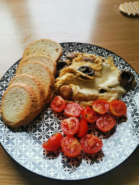 a plate of food with bread and tomatoes on a table at Modern Room With A Great Sunrise - close to the center - in Timişoara