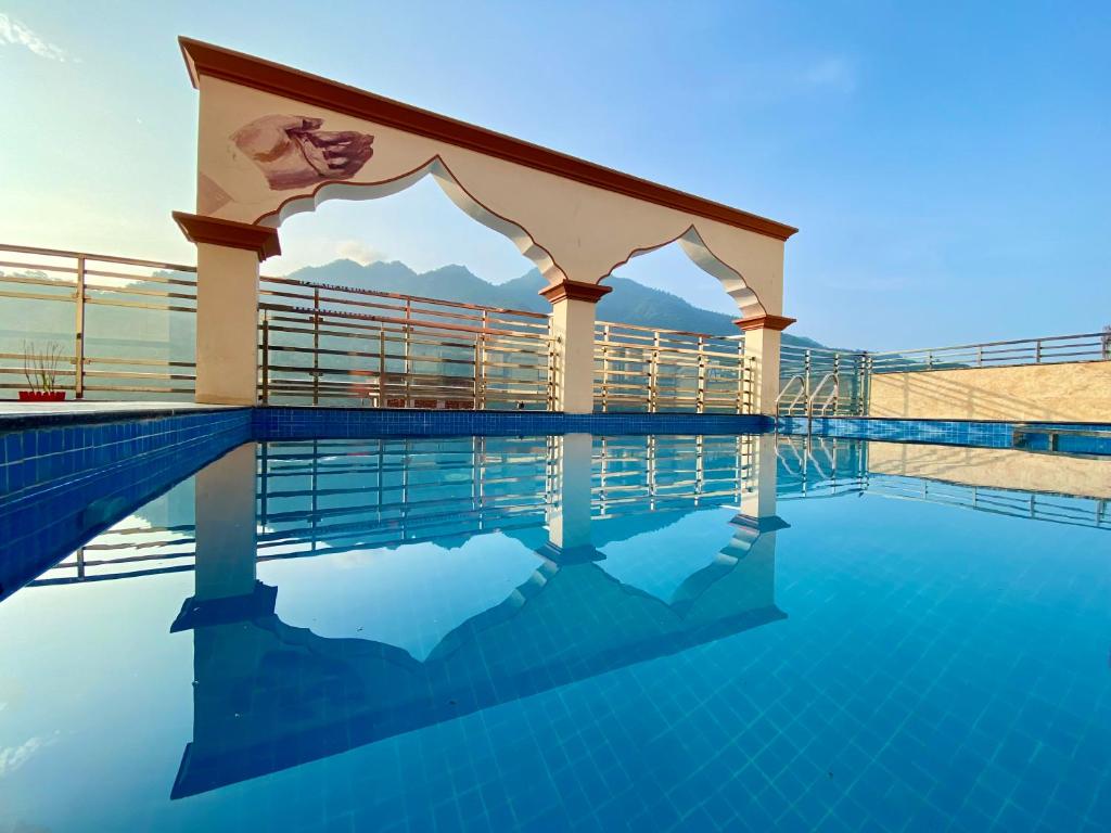 a pool at a resort with mountains in the background at Arogyadham Retreat in Rishīkesh