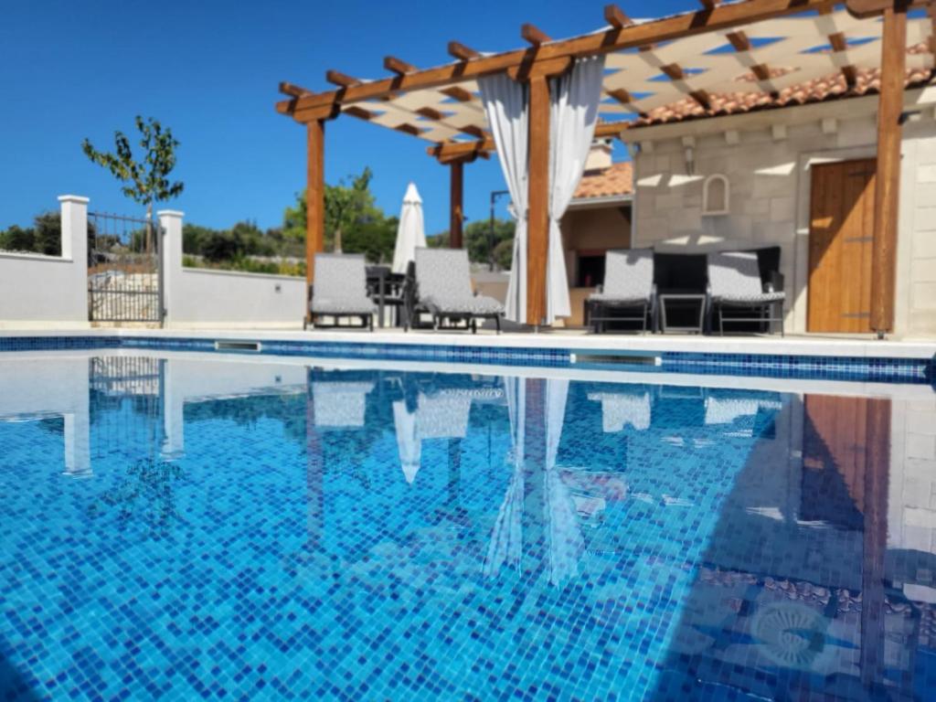 a swimming pool with chairs and a pergola at Villa Ancora in Selca