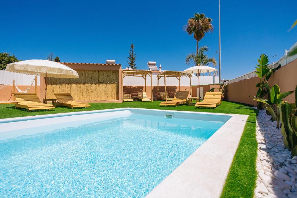 una piscina en un patio con sillas y sombrillas en Coral Boutique Suites, en Albufeira