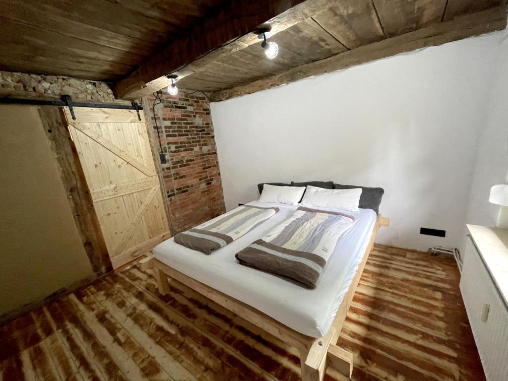 um quarto com uma cama com lençóis brancos e pisos em madeira em Fachwerkhaus in Alfhausen 