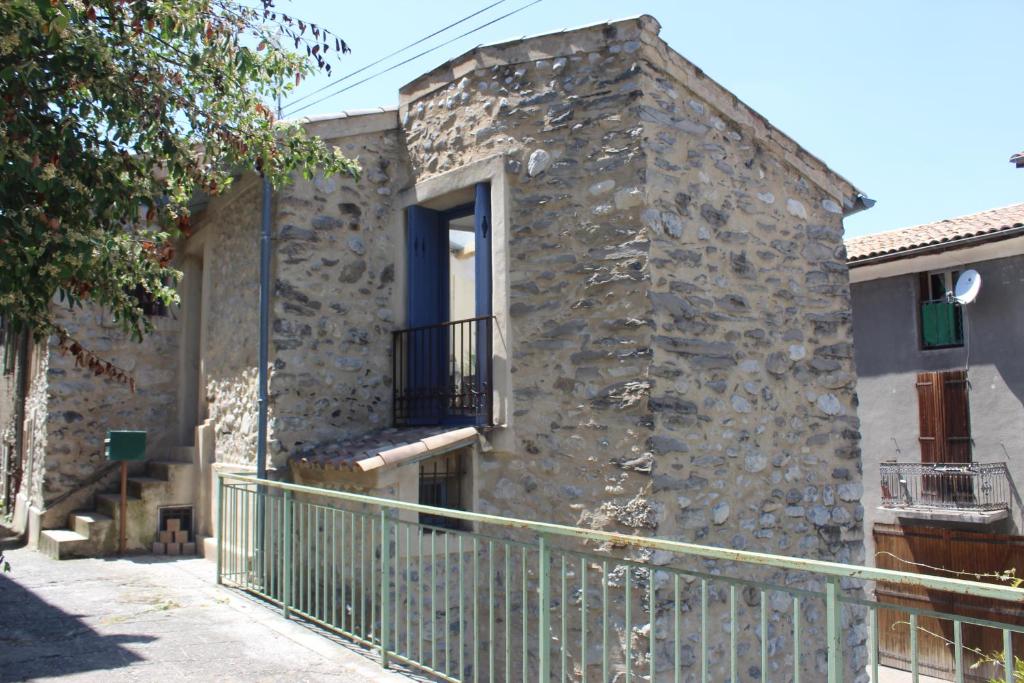 - un bâtiment en pierre avec un balcon et une fenêtre dans l'établissement Maison de village, à La Javie