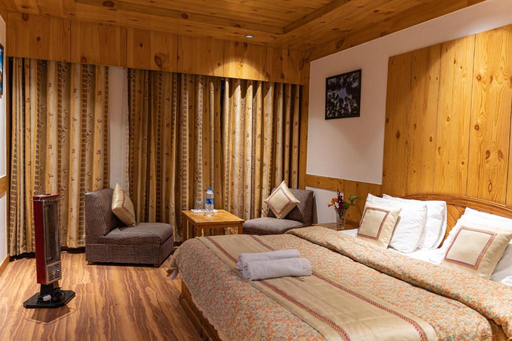 ein Hotelzimmer mit 2 Betten und einem Stuhl in der Unterkunft THE CONIFER in Manali