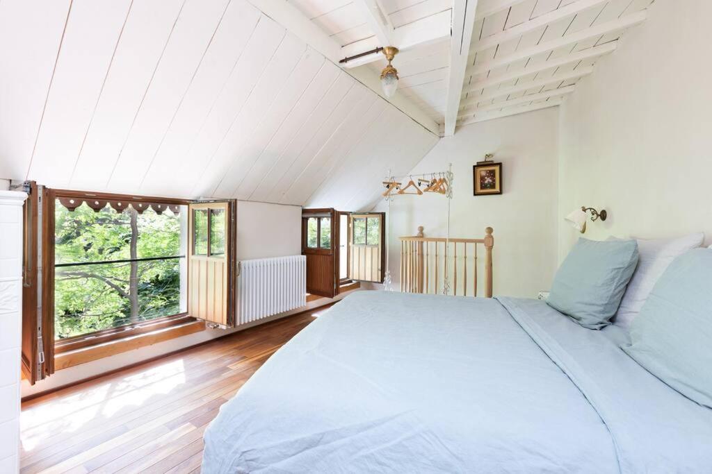 Carriage House in quiet ecological garden في أنتويرب: غرفة نوم بسرير كبير ونافذة كبيرة