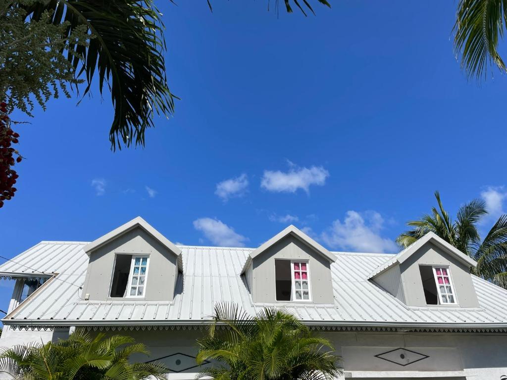 聖若瑟的住宿－ti sable appartement à 5 minutes de la mer，白色的房子,有白色的屋顶和棕榈树