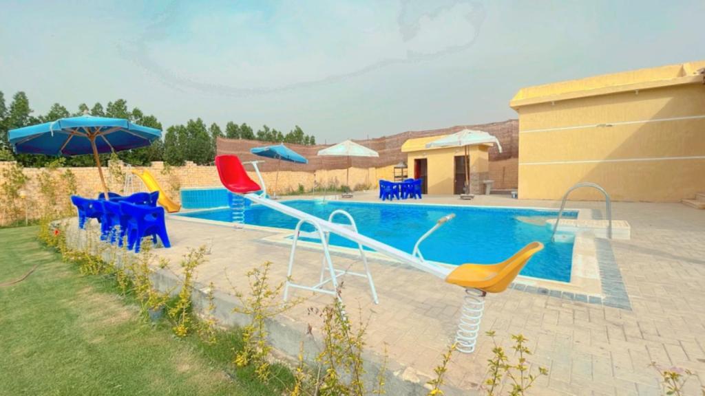 einen Pool mit Stühlen und Sonnenschirmen neben einem Pool in der Unterkunft تيوليب فيلا in Madinat as-Sadis min Uktubar