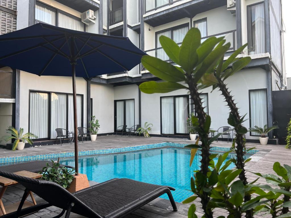 a swimming pool with a table and an umbrella at Rumah Kahyangan in Canggu