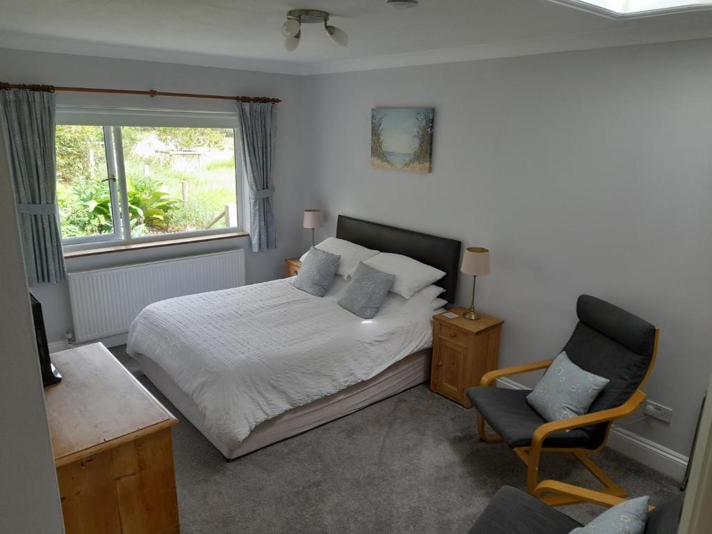 a bedroom with a bed and a chair and a window at North Headborough in Haverfordwest