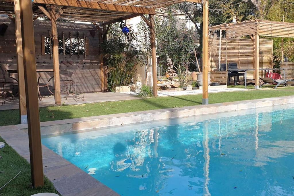 een zwembad in een achtertuin met een pergola bij Petite villa en bois avec piscine in Montbazin