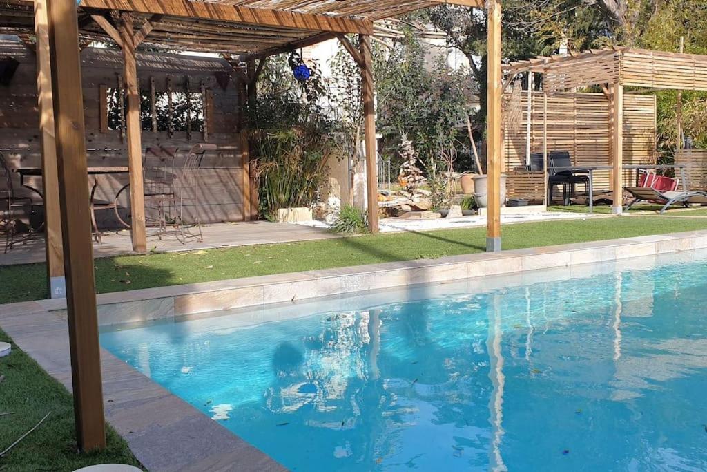 a swimming pool in a backyard with a pergola at Petite villa en bois in Montbazin