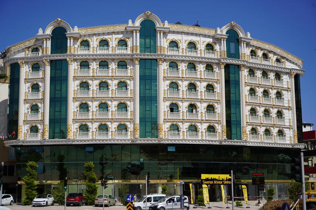 um grande edifício com carros estacionados em frente em Can Adalya Palace Hotel em Antália