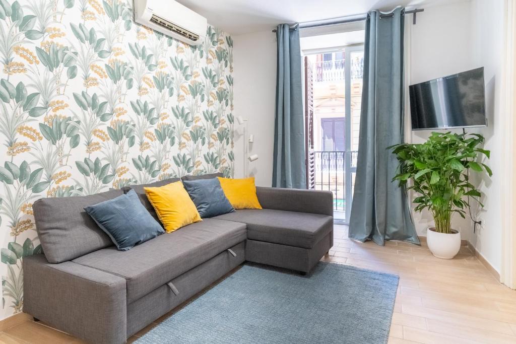 ein Wohnzimmer mit einem grauen Sofa und gelben Kissen in der Unterkunft Four Luxury Apartment in Palermo