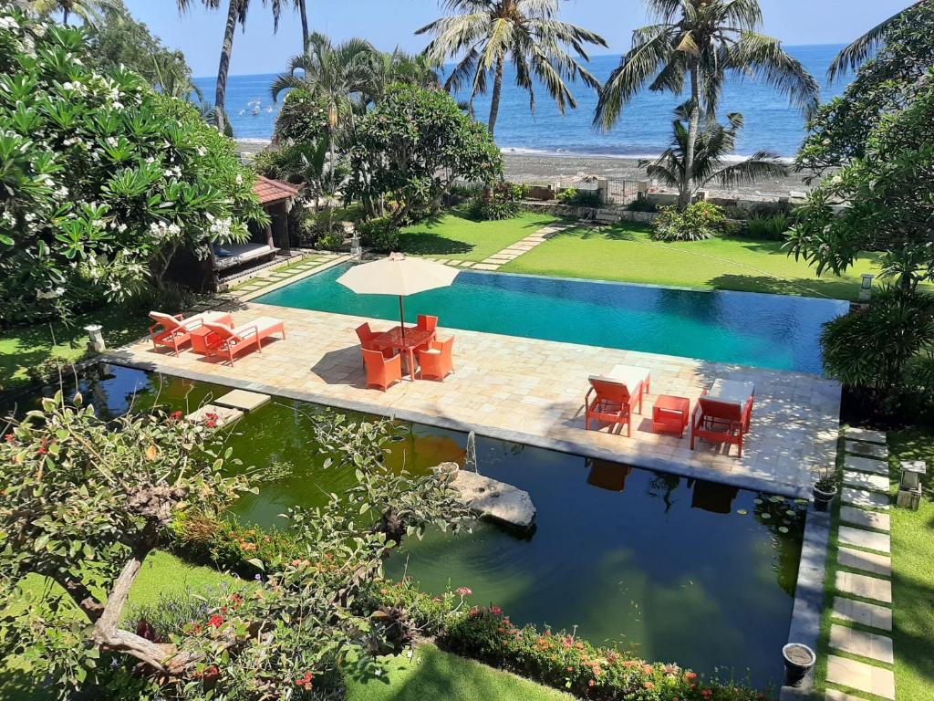 uma imagem de uma piscina com cadeiras e um guarda-sol em Villa Singkenken em Kubutambahan