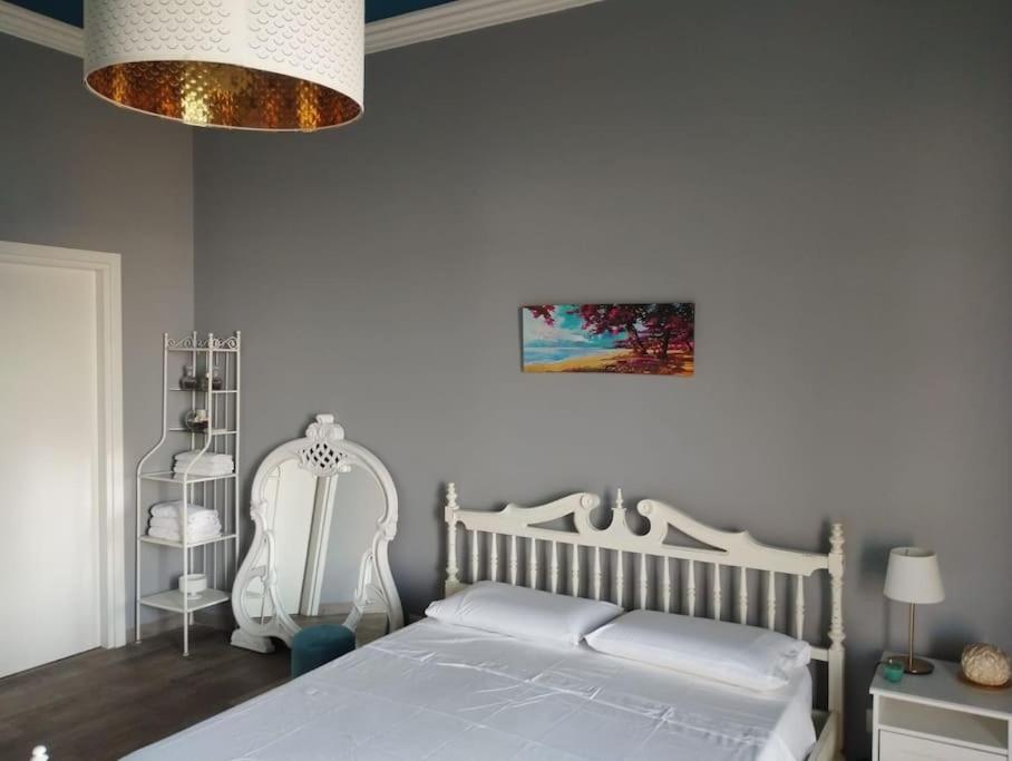 um quarto com uma cama branca e um lustre em Benedettini House em Catânia