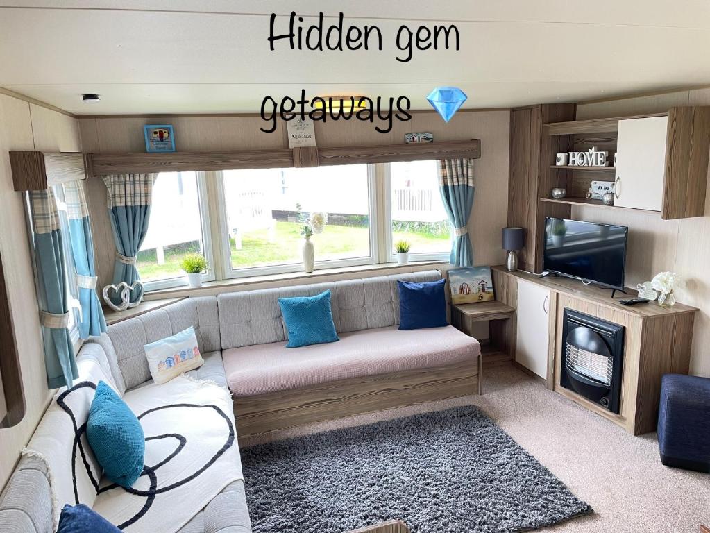 a caravan living room with a couch and a tv at Hidden Gem Getaways in Wyke Regis