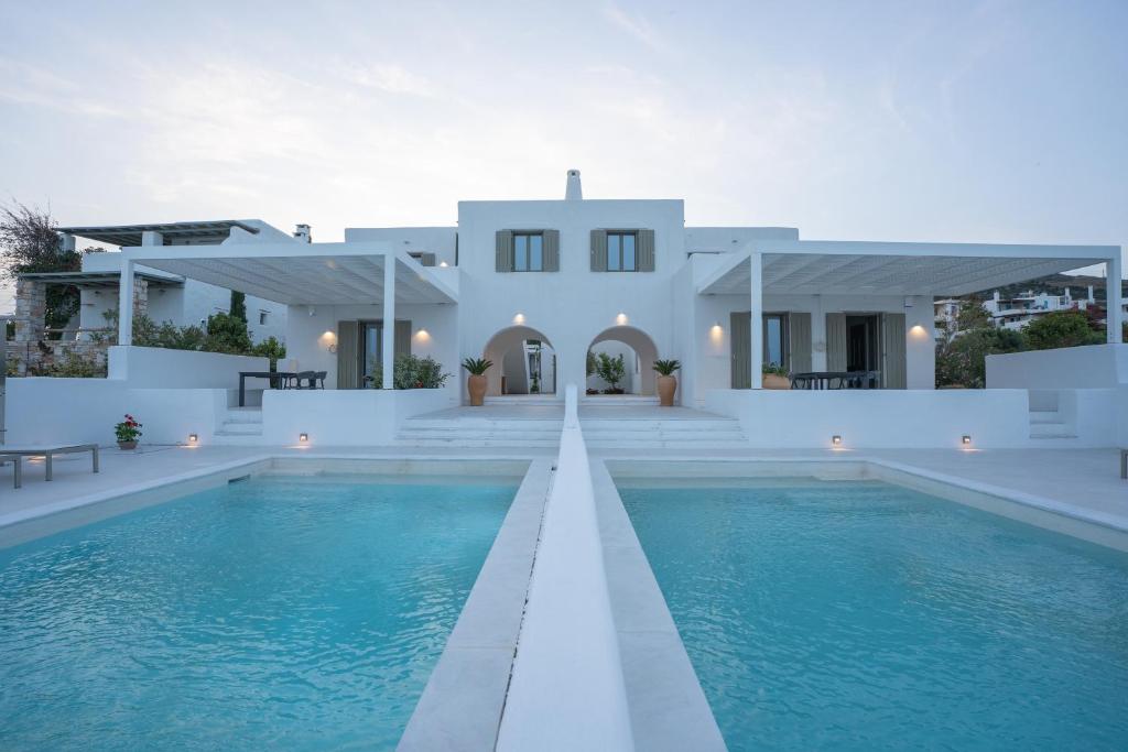 a villa with a swimming pool in front of a house at Paros Breeze Luxury Villa in Drios